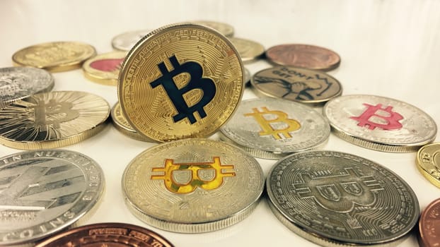 Cryptocurrency physical gold bitcoin coin near silver and brass bitcoins.