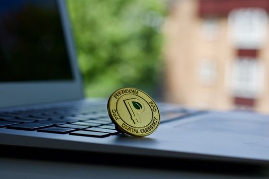 Cryptocurrency physical gold peercoin coin on the black computer keyboard.