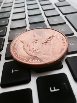 Digital currency physical brass dogecoin coin on the black computer keyboard.