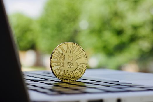 Cryptocurrency physical gold bitcoin coin on the black computer keyboard.