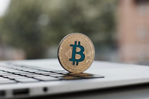 Cryptocurrency physical gold bitcoin coin on the black computer keyboard.