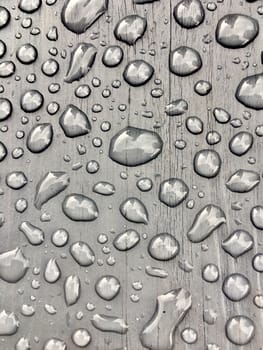 rain drops on on grey wooden bench 