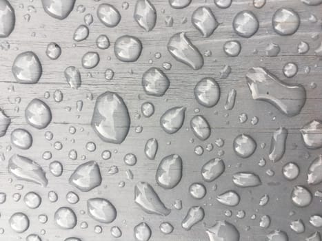 rain drops on on grey wooden bench 