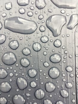 rain drops on on grey wooden bench 