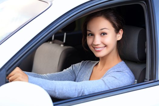 Beautiful woman driver smiling to you from her car