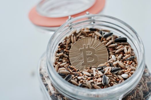 Cryptocurrency physical gold bitcoin coin in jar with seeds.
