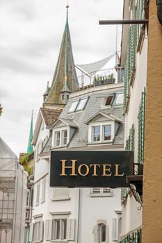 Hotel sign, metal letters, facade of old houses in downtown european city in background