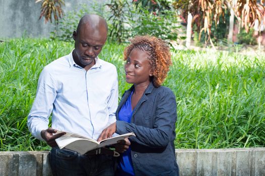 These young people gathered in a park looking for job in a magazine.