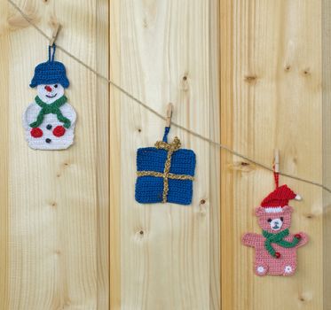 Several crocheted christmas hangers on a cord on wood, background