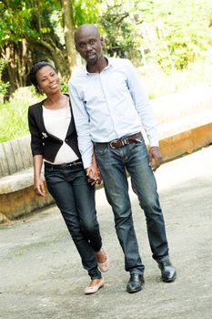 This couple , hand in hand stroll in a park.