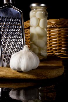 Marinated and fresh garlic with a grater on a dark background