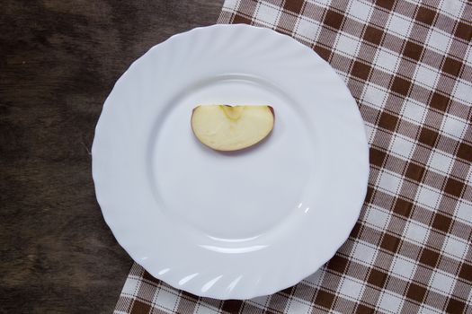 White plate with a slice of apple on a wooden table