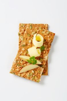 two butter curls and apple slices on pumpkin seed crackers
