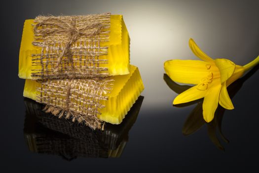 Handmade soap flower yellow on a black background with reflection
