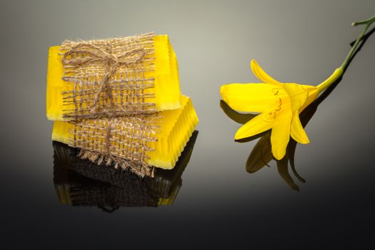 Handmade soap flower yellow on a black background with reflection