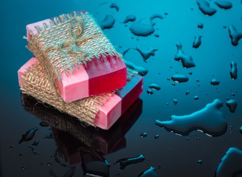 Handmade soap red on a blue background with drops of water