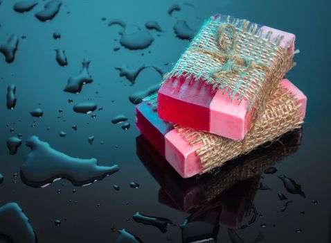 Handmade soap red on a blue background with drops of water