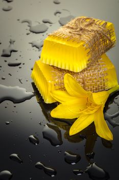 Handmade soap yellow on a black background with drops of water