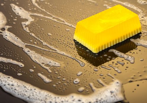 Handmade soap yellow on a black background with foam