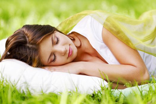 Beautiful young woman sleeping on grass outdoors