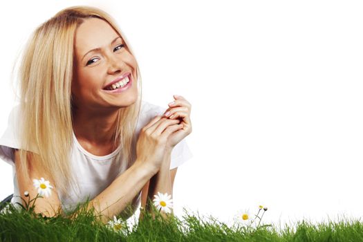 Beautiful young blonde woman lying on grass with chamomile flowers, isolated on white background