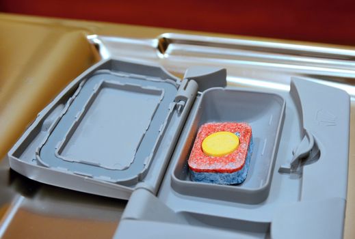 Detergent tablet in box in a dishwasher.