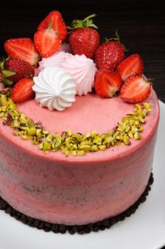 Chocolate strawberry cake decorated with berries, meringue and pistachios