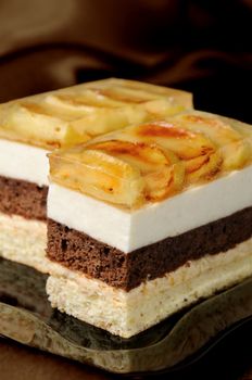 Cake stacked from caramel, apple mousse, chocolate and almond biscuit with a jelly layer of slices caramelized apple