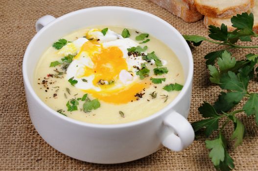 potato cream soup with bacon and poached eggs, herbs, spices