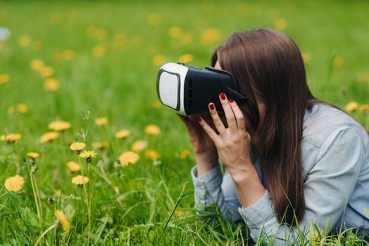 Woman using the virtual reality headset outdoors laying in spring flower field