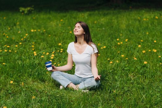 Beautiful young woman enjoy nature sitting in park with coffee