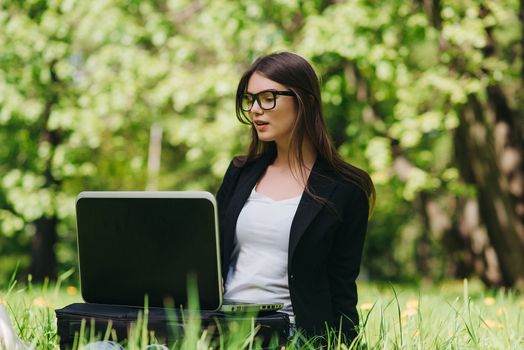 Beautiful business woman in suit using laptop computer in the park