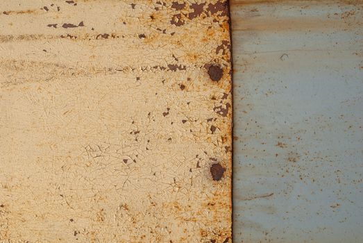 rusty iron surface covered with old chipped beige color paint, which has long been influenced by different climatic conditions