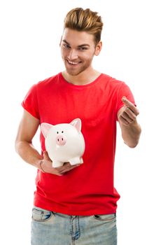 Handsome young holding a piggybank and smiling, isolated over a white background