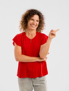 Portrait of a smiling middle aged brunette pointing with her left arm