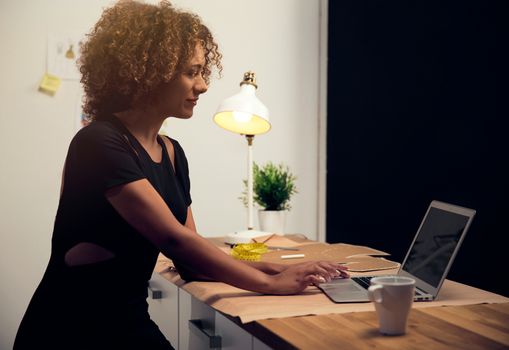 A young fashion designer on her atelier working with a laptop