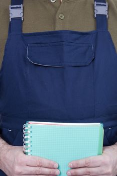 Notebook for notes in the hands of a worker in overalls