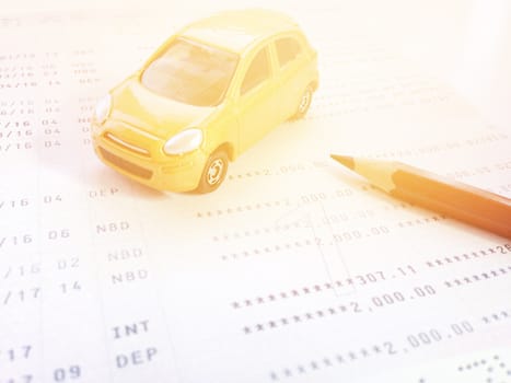 Business, finance, savings, banking or car loan concept : Miniature car model, pencil and savings account passbook or financial statement on white background