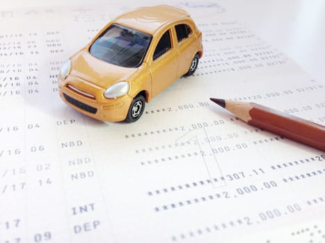 Business, finance, savings, banking or car loan concept : Miniature car model, pencil and savings account passbook or financial statement on white background