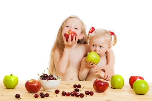 two little girls eat fruit at a table on the isolated background