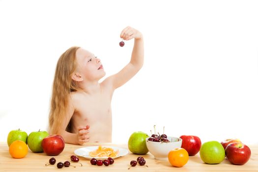 the little girl is fruit at a table on the isolated background