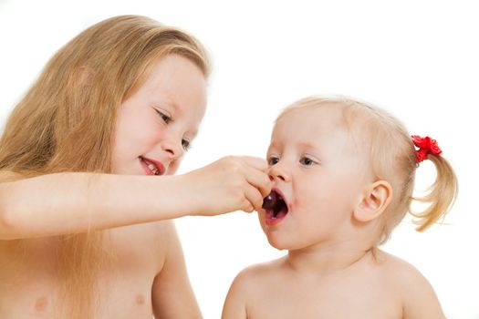 two little girls eat sweet cherry on the isolated background