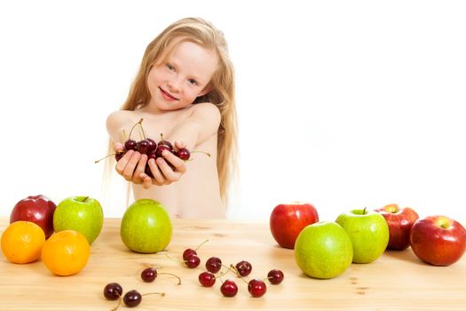 the little girl is fruit at a table on the isolated background