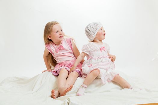 two little girls sit on the isolated background