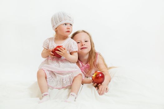 two little girls sit on the isolated background