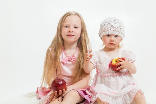 two little girls sit on the isolated background