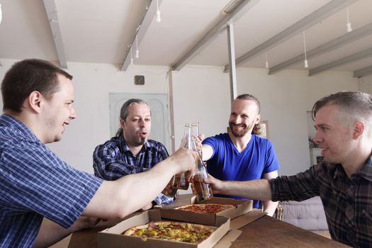 Male friends sitting at home, clink beer, going to eat pizza, celebrating something