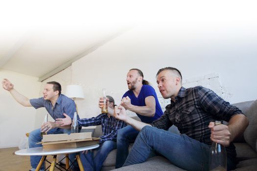 Male friends sports fans watching winning football match on TV at home celebrating winning goal huddled on couch shouting excited sharing snacks drinking beer
