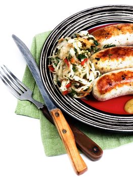 Delicious Grilled White Munich Sausages with Pickled Cabbage and Mustard Sauce on Red Striped Plate isolated on White background