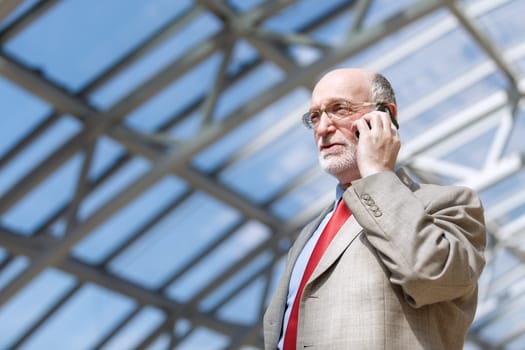 Senior businessman walking and having a conversation at phone